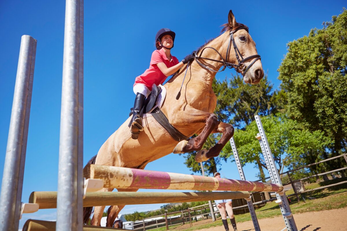 Fille à cheval franchissant un obstacle sur un parcours